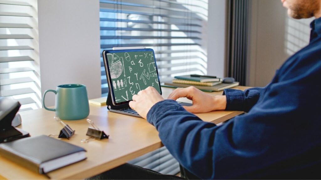 自宅の机でタブレットを使い、画面に数式や文字が表示されている男性の横顔。