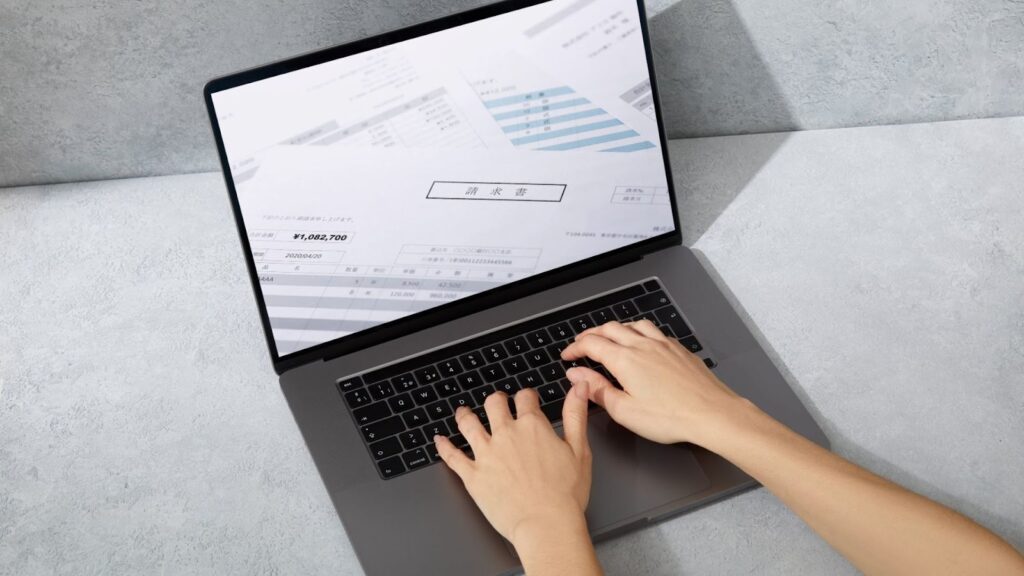 ノートパソコンで日本語の請求書を映している人の手元。